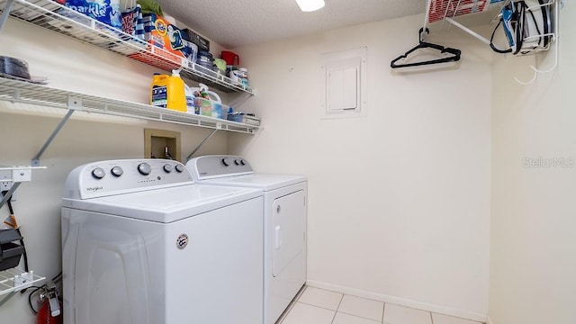 clothes washing area with light tile patterned floors, washing machine and clothes dryer, and a textured ceiling