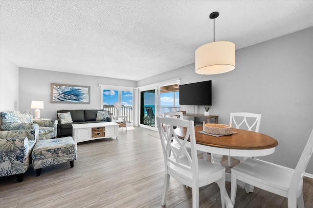 dining space with a textured ceiling and light wood-type flooring