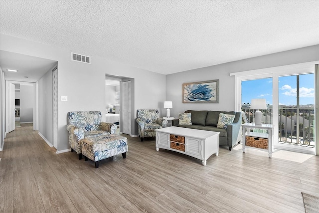 living room with a textured ceiling and light wood-type flooring