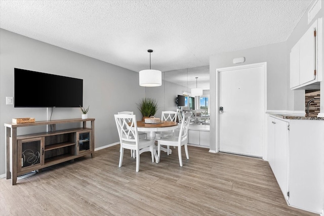 dining space featuring light hardwood / wood-style flooring and a textured ceiling