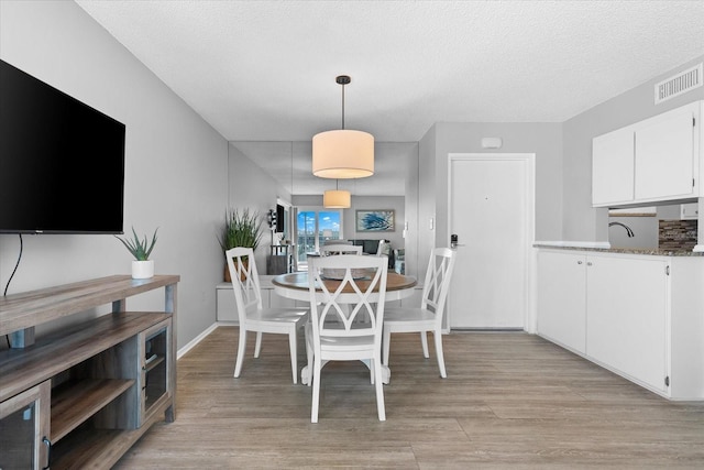 dining space featuring a textured ceiling and light wood-type flooring