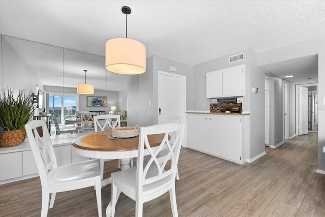 dining area with light hardwood / wood-style flooring and a textured ceiling