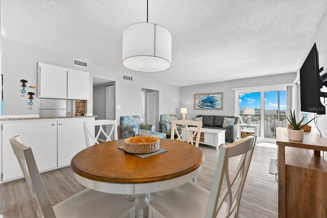 dining area featuring a textured ceiling and light wood-type flooring