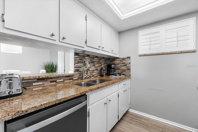 kitchen with white cabinetry, dishwasher, sink, dark stone countertops, and decorative backsplash