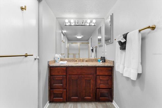 bathroom with hardwood / wood-style flooring, vanity, a textured ceiling, and a shower with shower door