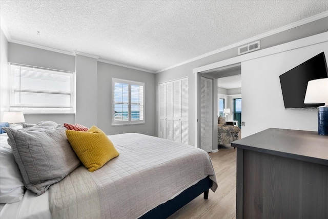 bedroom with ornamental molding, a textured ceiling, and light wood-type flooring