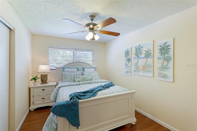 bedroom with dark wood-type flooring, ceiling fan, and a textured ceiling