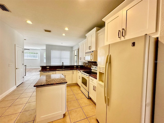 kitchen featuring sink, white cabinetry, light tile patterned floors, a kitchen island, and white appliances