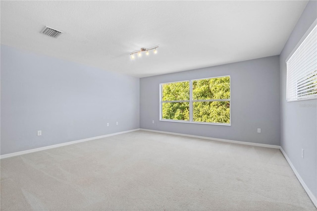 carpeted empty room featuring rail lighting