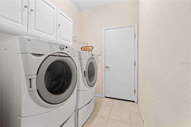 clothes washing area with light tile patterned floors, cabinets, and washing machine and clothes dryer