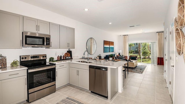 kitchen with stainless steel appliances, sink, kitchen peninsula, light tile patterned floors, and gray cabinetry