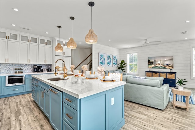 kitchen featuring blue cabinets, white cabinets, pendant lighting, light hardwood / wood-style flooring, and sink