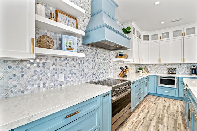 kitchen featuring white cabinetry, custom exhaust hood, appliances with stainless steel finishes, blue cabinetry, and backsplash