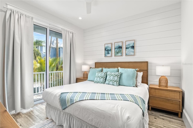 bedroom featuring light wood-type flooring, ceiling fan, wood walls, and access to outside