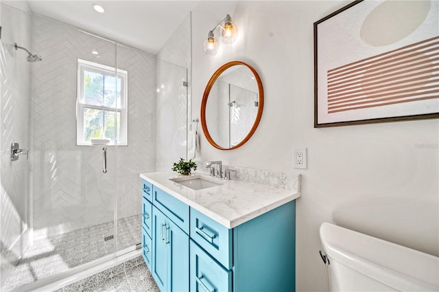 bathroom with toilet, vanity, and a shower with shower door