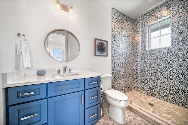 bathroom with toilet, vanity, and a tile shower