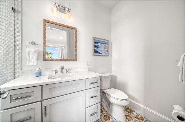 bathroom with toilet, vanity, and tile patterned flooring