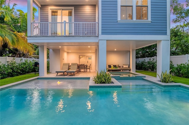 rear view of property featuring a balcony, a pool with hot tub, and a patio