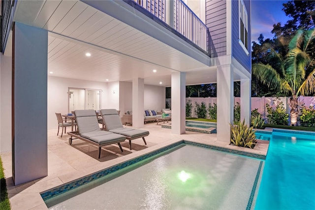 pool at dusk featuring a jacuzzi and a patio