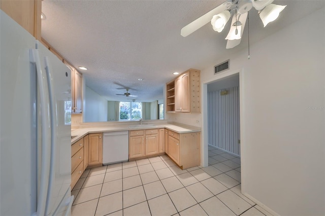 kitchen with sink, white appliances, a textured ceiling, light tile patterned flooring, and light brown cabinets