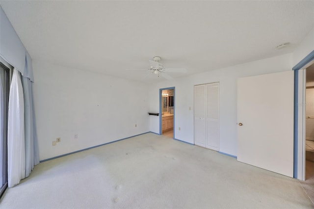 unfurnished bedroom with connected bathroom, light colored carpet, a closet, and ceiling fan