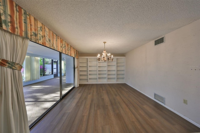 unfurnished dining area with dark wood-type flooring, a chandelier, and a textured ceiling