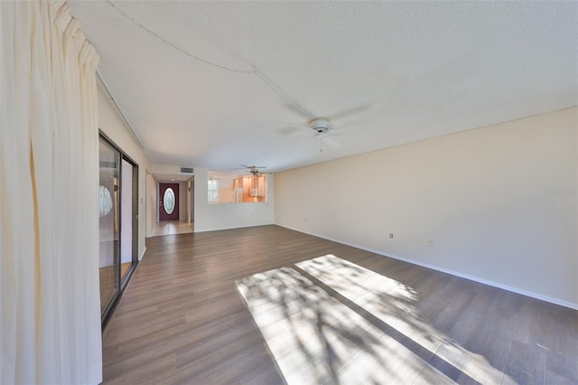 unfurnished living room featuring ceiling fan, dark hardwood / wood-style floors, and a textured ceiling