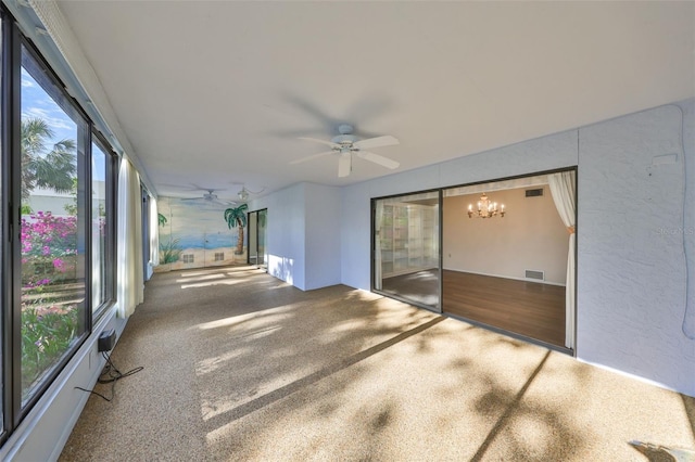 unfurnished sunroom with ceiling fan with notable chandelier