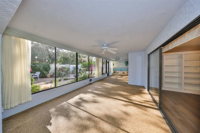 unfurnished sunroom featuring ceiling fan and a healthy amount of sunlight