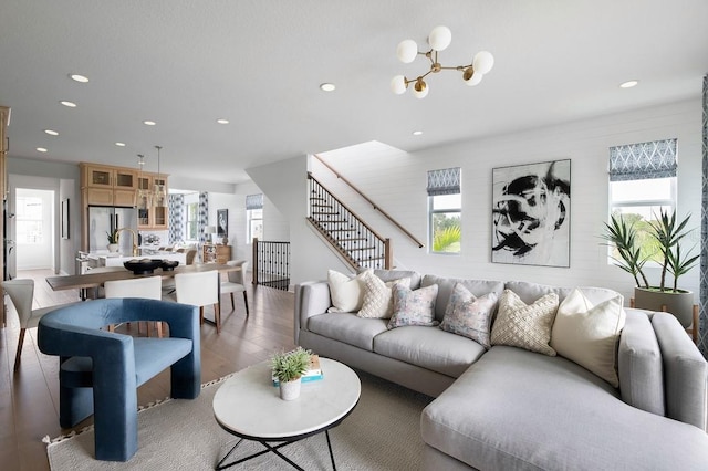 living room featuring wood-type flooring, a wealth of natural light, and an inviting chandelier