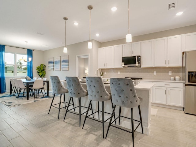 kitchen with pendant lighting, white cabinetry, and stainless steel appliances