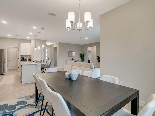 dining space with an inviting chandelier, sink, and light wood-type flooring