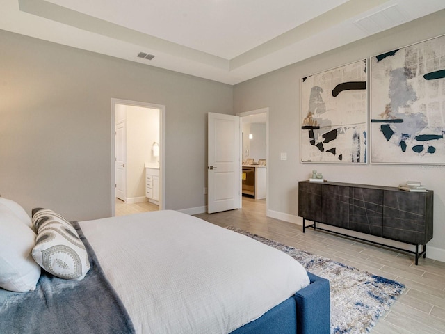 bedroom with ensuite bath and a raised ceiling