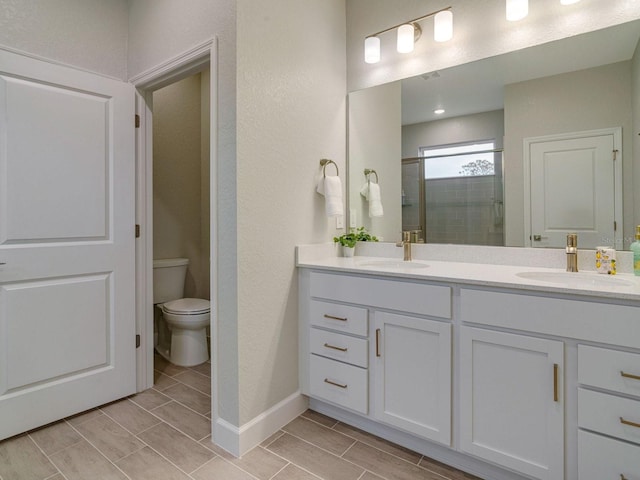 bathroom featuring vanity, toilet, and a shower with shower door