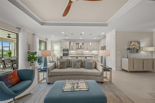 living room with light tile patterned flooring, a healthy amount of sunlight, a tray ceiling, and sink