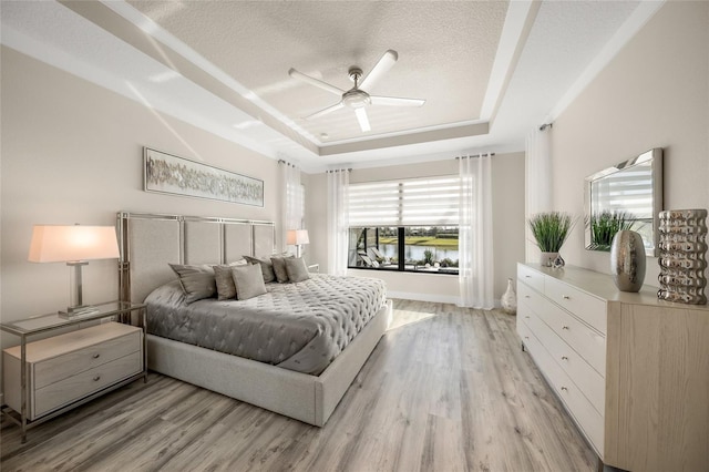 bedroom featuring ceiling fan, light hardwood / wood-style flooring, a raised ceiling, and a textured ceiling