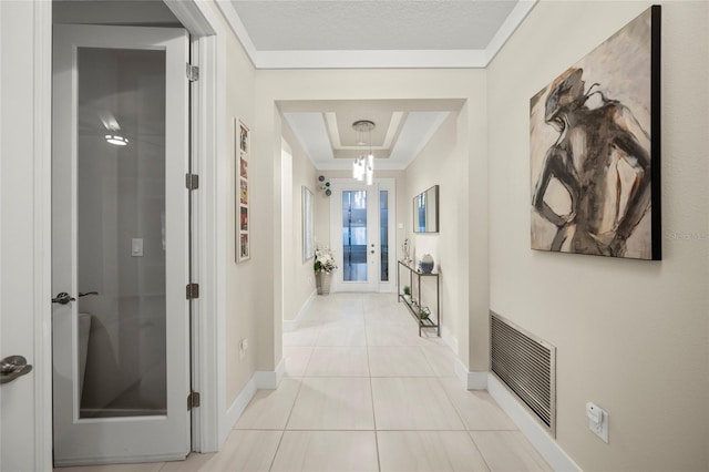 hallway featuring a raised ceiling, crown molding, and light tile patterned floors