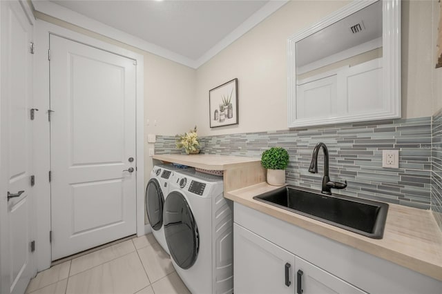 laundry room featuring sink, light tile patterned floors, cabinets, ornamental molding, and washer and dryer