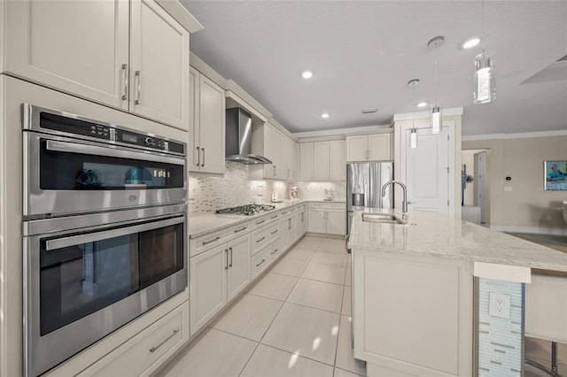 kitchen featuring pendant lighting, stainless steel appliances, white cabinets, a center island with sink, and wall chimney exhaust hood