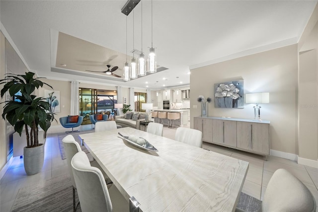 dining room featuring a raised ceiling, light tile patterned floors, and ceiling fan