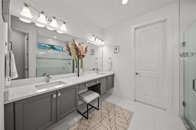 bathroom with a shower with door, vanity, and tile patterned floors