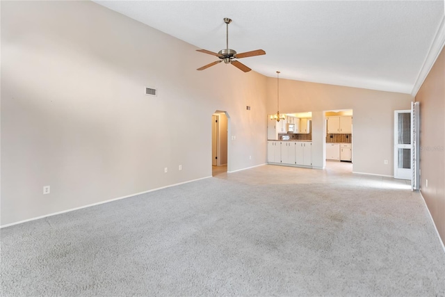 unfurnished living room with ceiling fan with notable chandelier, light colored carpet, and high vaulted ceiling