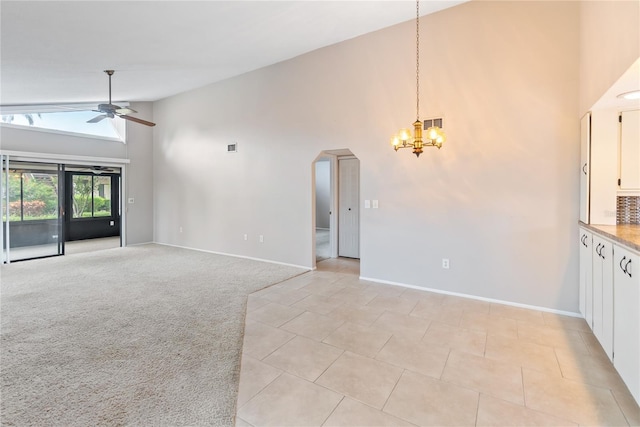 unfurnished living room with light carpet, ceiling fan with notable chandelier, and high vaulted ceiling