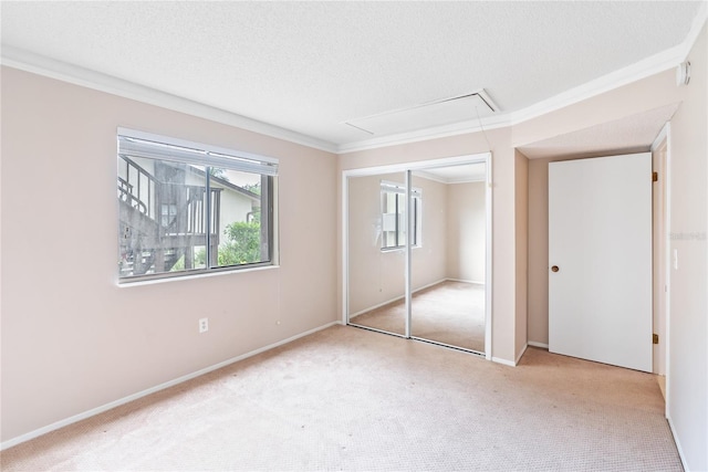 unfurnished bedroom with a textured ceiling, light carpet, a closet, and crown molding