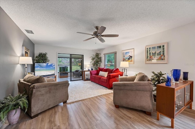 living room featuring ceiling fan, wood-type flooring, and a textured ceiling