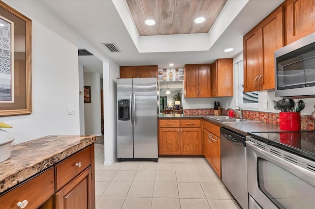 kitchen featuring light tile patterned flooring, stainless steel appliances, a tray ceiling, and sink