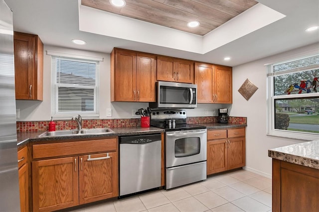 kitchen with sink, light tile patterned floors, a raised ceiling, and appliances with stainless steel finishes