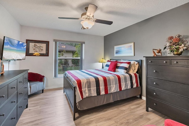 bedroom featuring ceiling fan, light hardwood / wood-style floors, and a textured ceiling