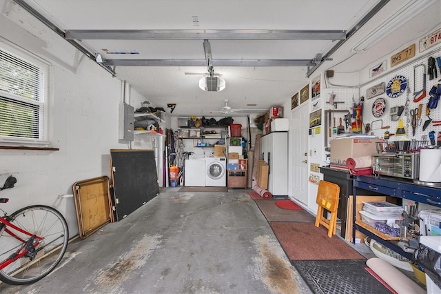 garage featuring washing machine and clothes dryer, a garage door opener, and a workshop area