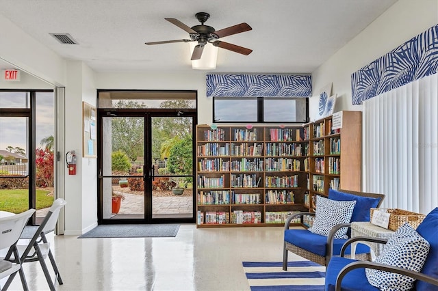 sitting room featuring ceiling fan, a wealth of natural light, french doors, and a textured ceiling